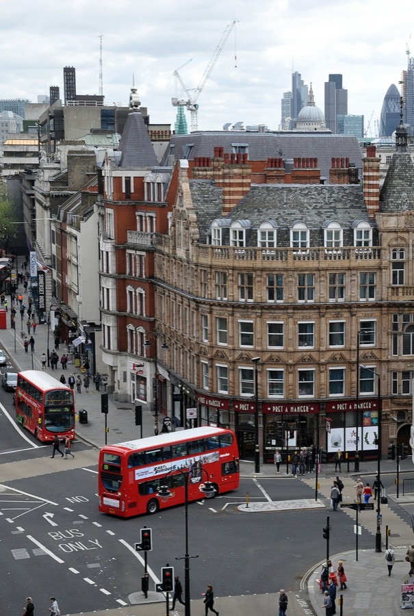 A London street with a red double-decker bus and the city skyline behind